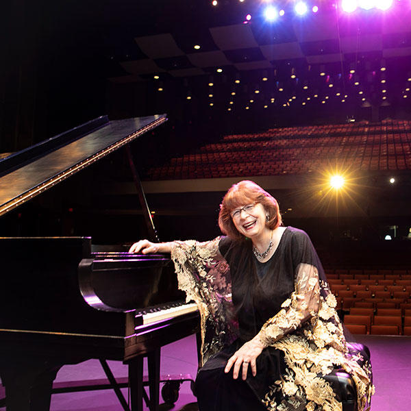 Linda Monson sitting at the grand piano at the Center for the Arts